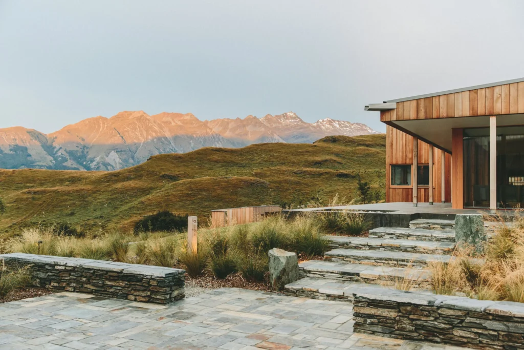 Modern house with mountainous landscape at sunset.